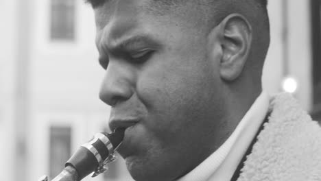 Black-And-White-And-Close-Up-View-Of-A-Man-In-Jacket-Playing-Sax-In-The-Street-1