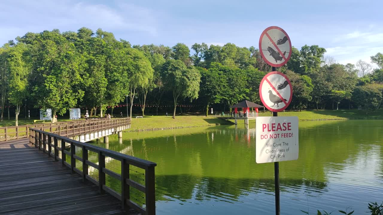 Sign prohibiting feeding fish and birds in the park, promoting cleanliness and preventing vandalism. Keep wildlife wild for a healthy environment.