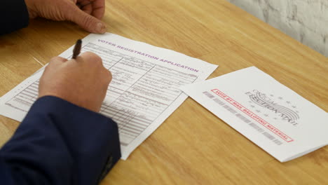person filling out voter registration application and mail-in ballot