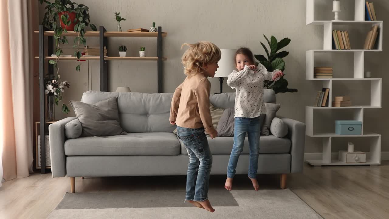 двое счастливых милых маленьких детей, веселящихся дома.