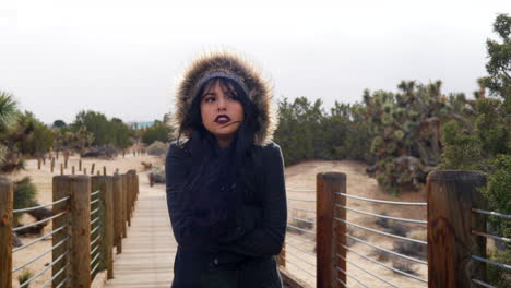 beautiful young woman shivering in the cold, stormy bad weather with rain drops under cloudy sky slow motion