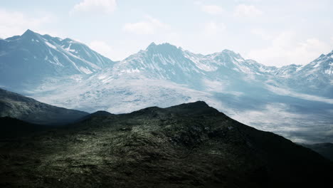 Aerial-Over-Valley-With-Snow-Capped-Mountains-In-Distance