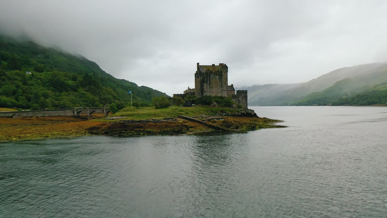 vista de avión no tripulado del castillo de eilean donan durante un vuelo a bajo nivel sobre el lago duich en marea baja