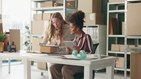 women working together in a small business office with boxes and a tablet