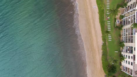 Flying-low-along-the-coast-of-Kihei,-Hawaii-on-a-sunny-day,-looking-down