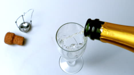 Champagne-being-poured-into-flute-on-white-surface-high-angle-view