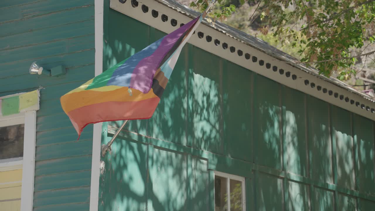 Images of a rainbow flag waving in front of a house