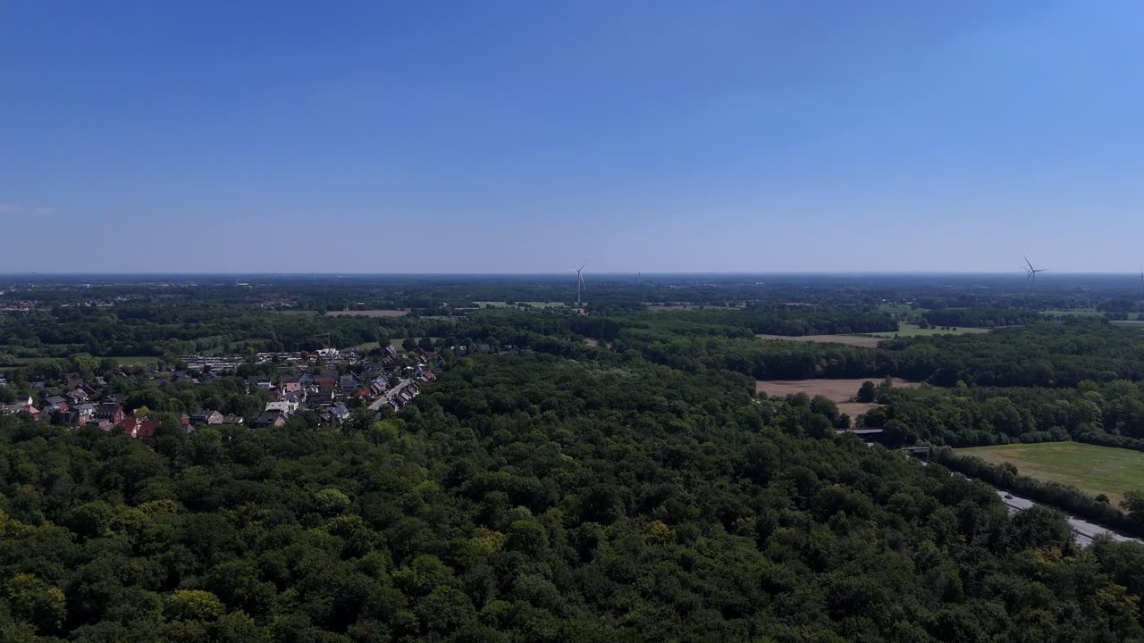 Picturesque forest landscape with green trees and small town in suburb of America. Cars on interstate highway at blue sky and sunlight. Aerial forward wide shot