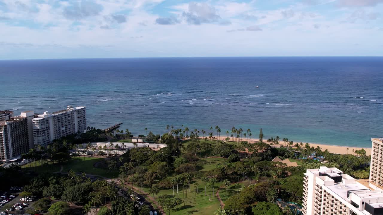 An expansive aerial view of Honolulu's skyline and the serene Oahu coastline captured by drone, under blue skies. This video highlights urban architecture and stunning ocean vistas