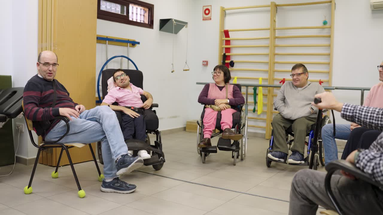 Group of people in wheelchairs having a conversation in a therapy room
