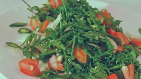 close up to a fiddlehead fern salad or pako salad being tossed, an authentic traditional filipino dish from the philippines