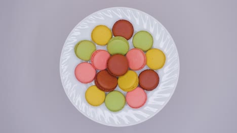 sweet color macaroons are rotating on white plate. top view.