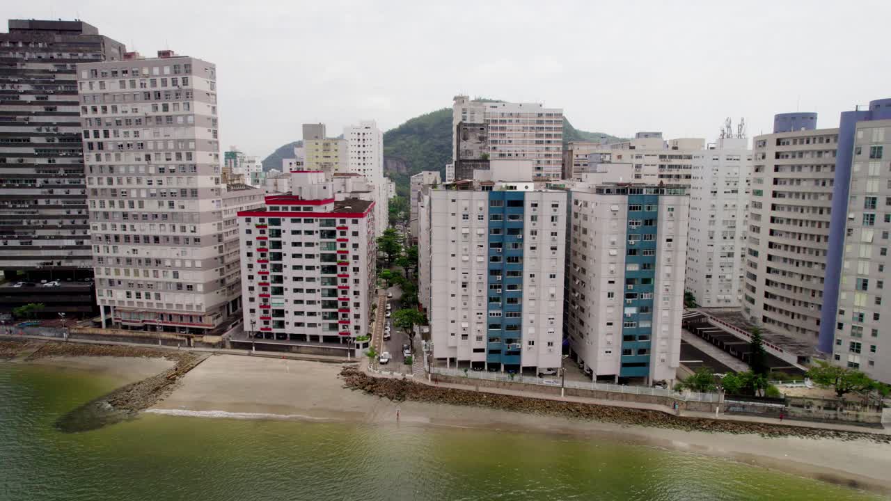 Tomada aérea do mar em direção à praia e aos edifícios da cidade de São Vicente