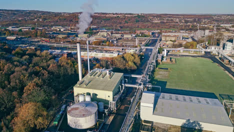 aerial footage moving towards a large industrial chemical plant, showing pipelines, metal structures, cooling towers and chemical storage