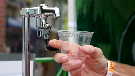 slow motion - water being poured into a plastic cup at an outdoor festival