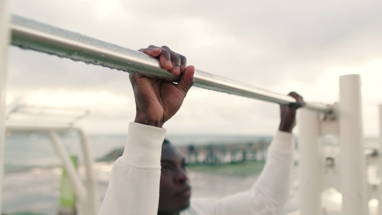 Close-up of Man's Hands Gripping Pull-Up Bar at Outdoor Gym