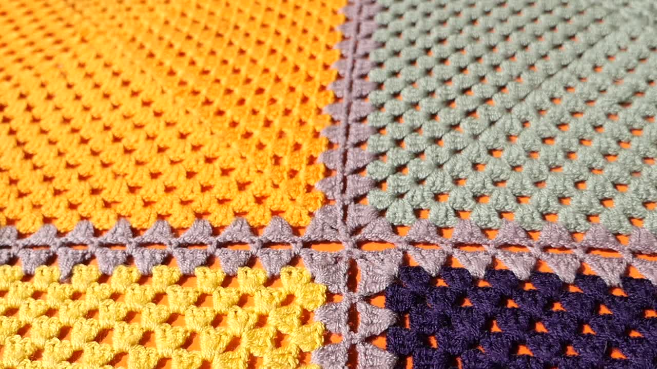 Hand holding a smartphone on a colorful crochet blanket