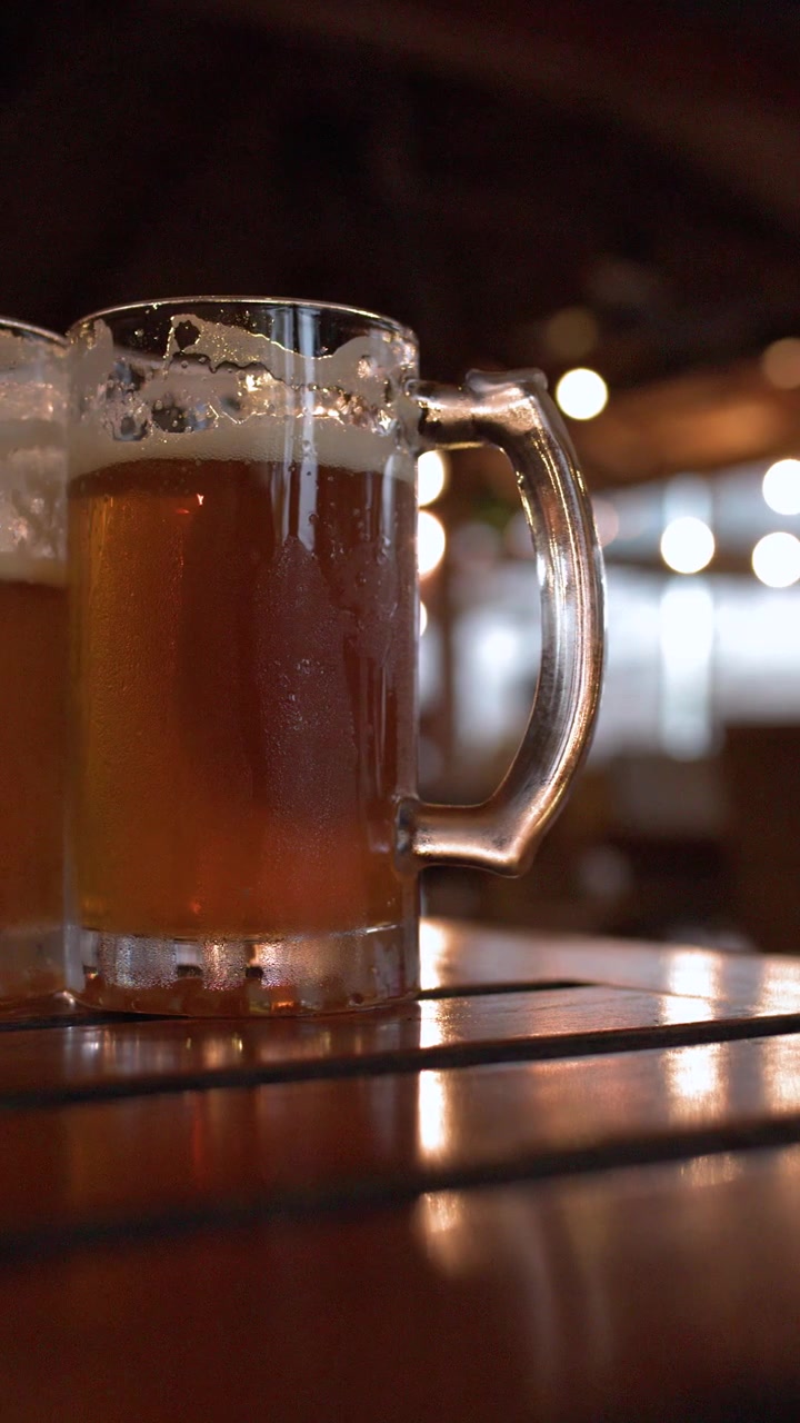 Boccali di birra lager fredda con condensa sono posizionati su un tavolo di legno in un bar