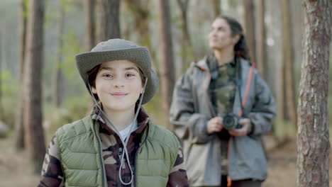 niño caucásico feliz en el bosque sosteniendo un libro y luego sonriendo a la cámara