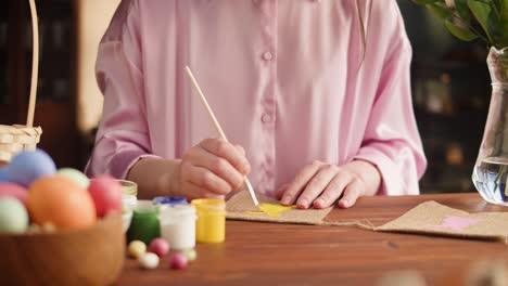 happy easter holiday. woman painting bunny on garland close-up. preparing for easter, decorating room, colored eggs. christian celebration, family traditions.