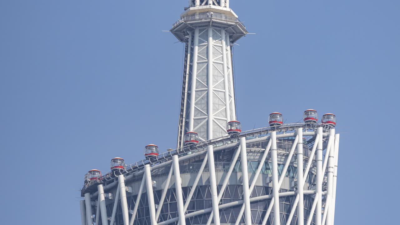 Modern Tower with Moving Observation Gondolas Against Blue Sky