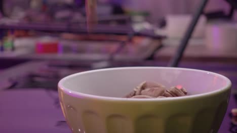 pecan nuts fall into a yellow bowl in a fast-motion, static shot.