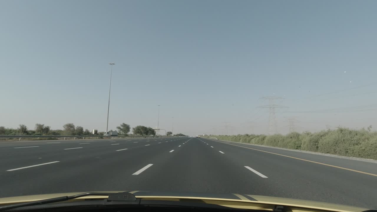 Solar powered street lights in the middle of desert freeway with 6 lane roads on both sides can be seen with high electrical towers on the right side.