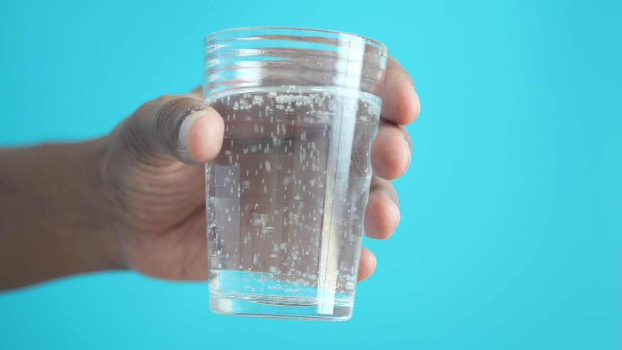 persona que sostiene un vaso de agua gaseosa