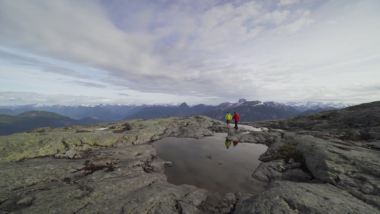 To personer vandrer på en bjergtop i farverige jakker i British Columbia, Canada