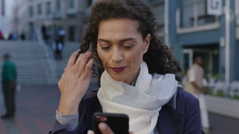 retrato en cámara lenta de una hermosa mujer de raza mixta enviando mensajes de texto navegando usando una aplicación de redes sociales para teléfonos inteligentes esperando en la ciudad