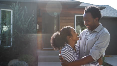 Portrait-Of-Hugging-Couple-Standing-Outdoors-In-Front-Of-House