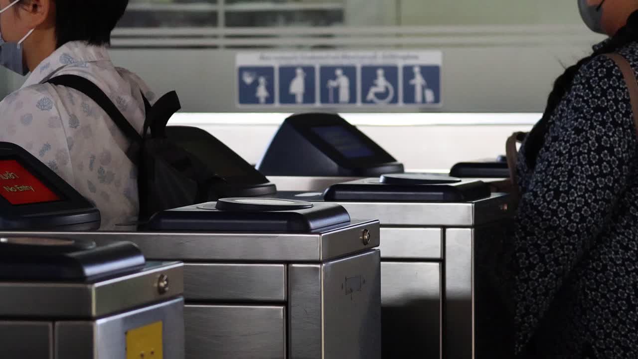 Person using a card to pass through a turnstile gate
