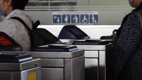 person using a card to pass through a turnstile gate