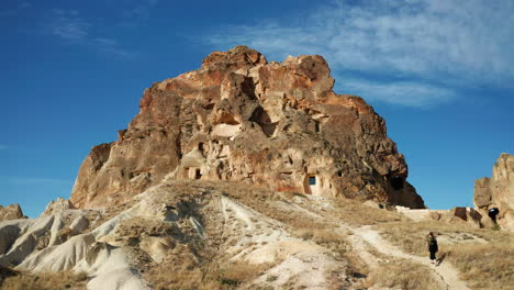 woman walking towards goreme rock formation with carved cave dwellings in turkey