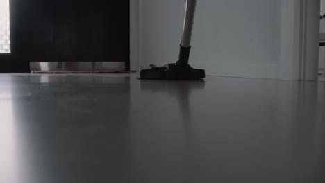 close up young male cleaning the house with a vacuum cleaner cleaning concrete floor