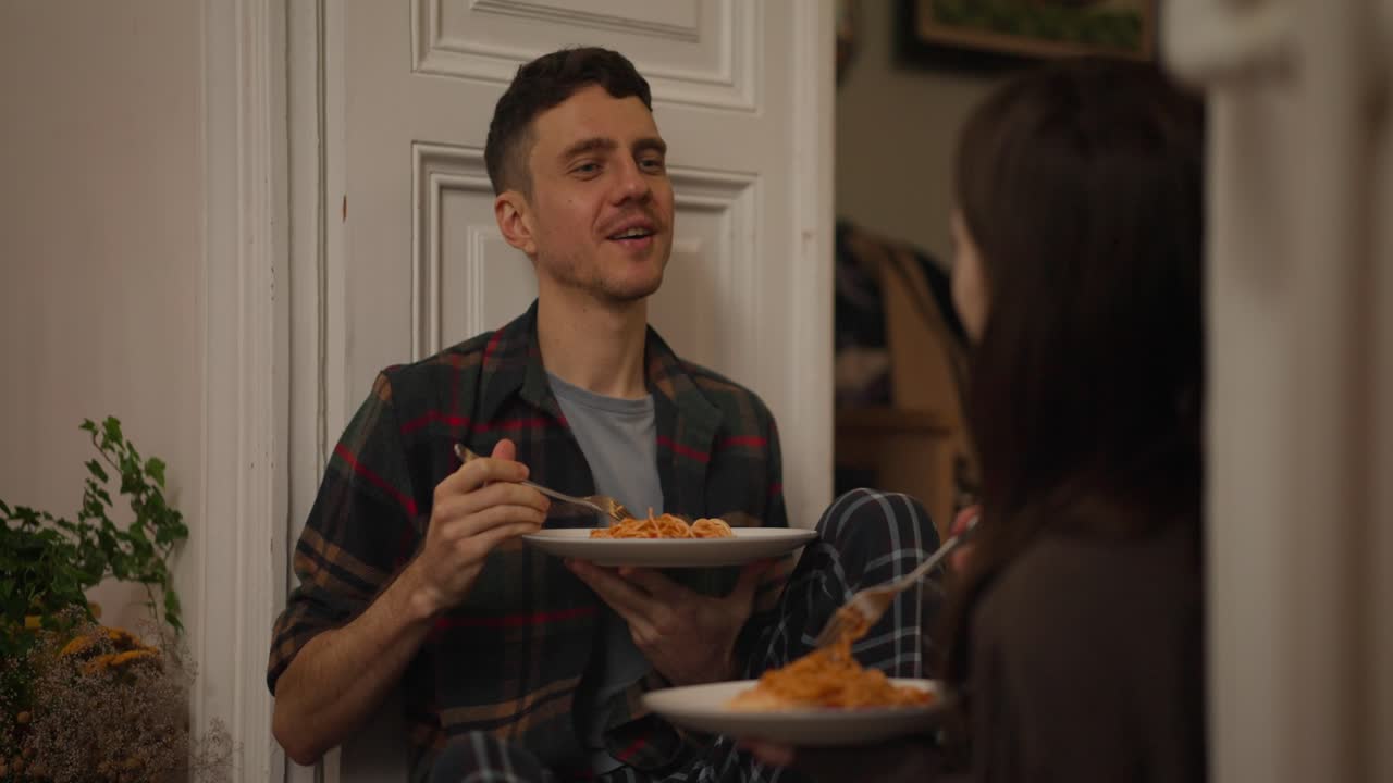 Couple eating spaghetti indoors
