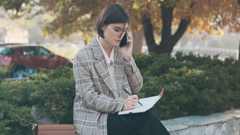 female entrepreneur writing in notepad while resting outdoor.