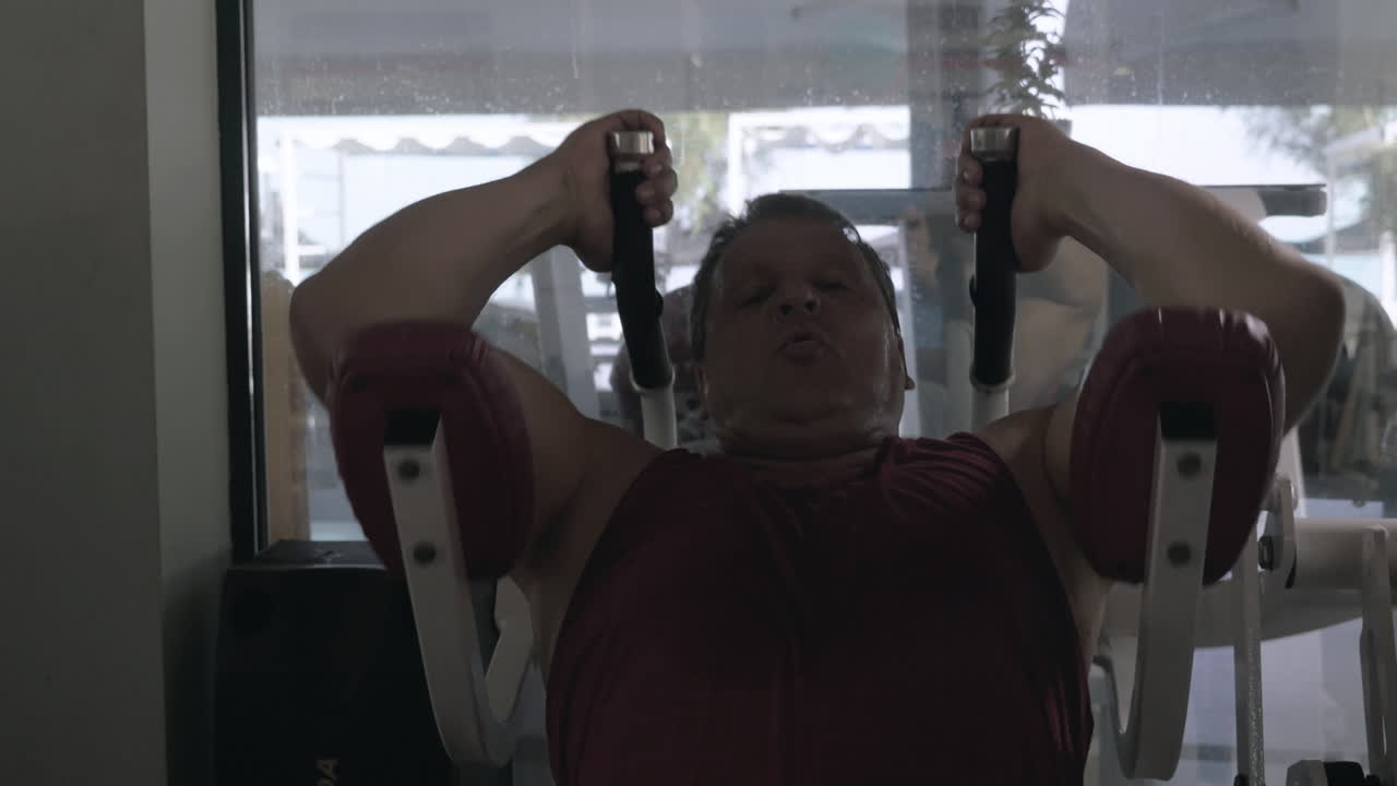 el hombre está haciendo ejercicios abdominales con simulador en el gimnasio y sudor