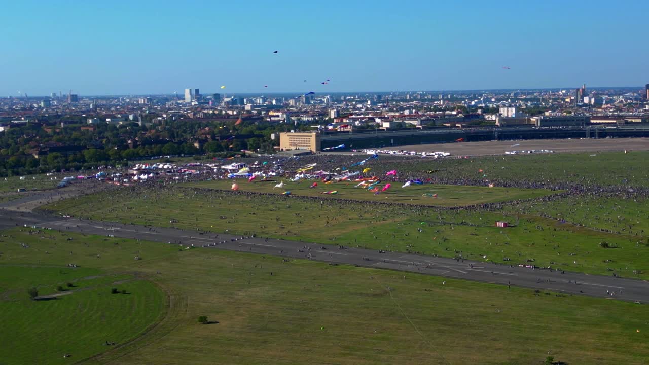 Large crowd of people gathering at the Tempelhofer Feld giant kite festival in Berlin, Germany. Unbelievable aerial view flight panorama orbit drone