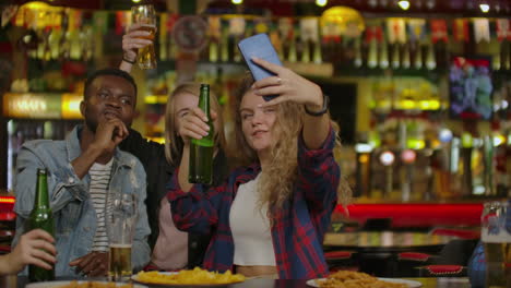 Happy-male-friends-taking-selfie-and-drinking-beer-at-bar-or-pub.-People-leisure-friendship-technology-and-party-concept---happy-male-friends-taking-selfie