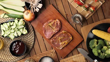 top down shoot of a steak lying on a wooden board surrounded by ingredients