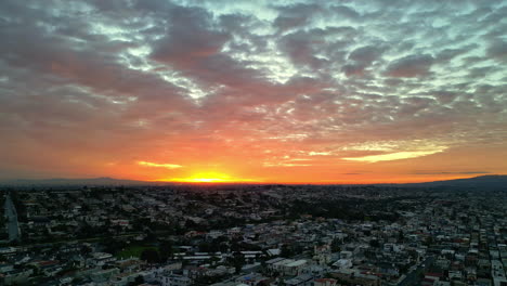 Aerial-view-of-city-lightened-by-stunning-sunset,-urban-area-merging-perfectly-with-nature