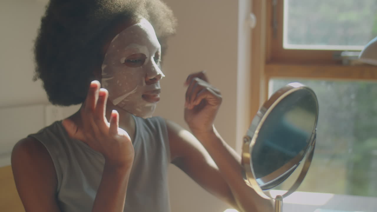 Donna afroamericana che applica una maschera per il viso a casa