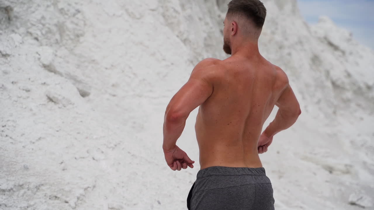 Young bodybuilder poses in nature. Handsome bodybuilder with perfect muscular body posing outdoors