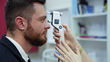 doctor checking eyes with device. ophthalmologist check eyesight of young man with modern equipment