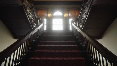 Alte-Große-Treppe-In-Einem-Herrenhaus-Aus-Dem-20.-Jahrhundert,-Durch-Dessen-Fenster-Die-Sonne-Scheint