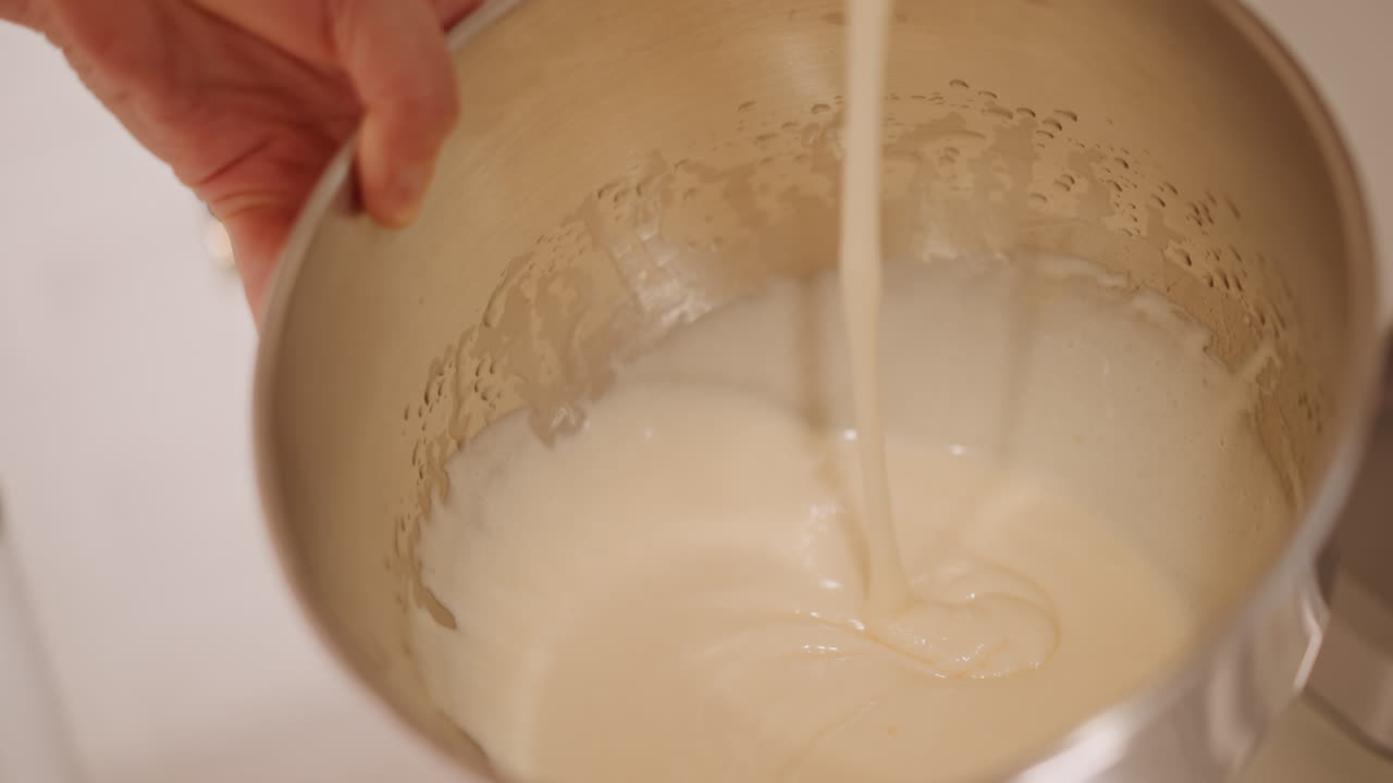 Un cuoco casalingo sta ultimando il ripieno cremoso di zucca per la torta in una ciotola d'acciaio, delicati colpi di frusta creano nastri setosi, primo piano di mani che uniformano la consistenza, calda profondità di campo, tocco finale intimo.