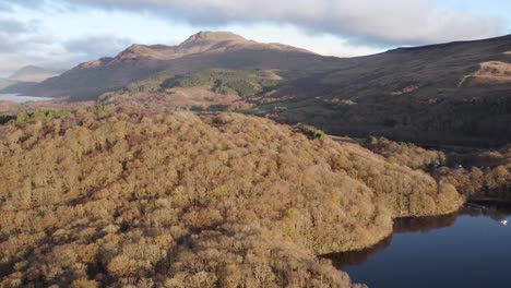 Imágenes-Aéreas-De-Drones-De-Un-Amanecer-De-Otoño-Sobre-El-Lago-Lomond-Y-La-Montaña-Ben-Lomond-En-El-Parque-Nacional-Del-Lago-Lomond-Y-Los-Trossachs-En-Escocia-Con-Bosques-Nativos-De-Hoja-Ancha-En-Primer-Plano