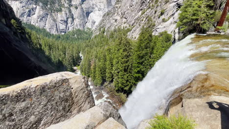 From-atop-a-mountain,-a-waterfall-pours-down-a-mountain