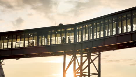 sunset silhouette of a terminal entrance, pedestrian bridge with people